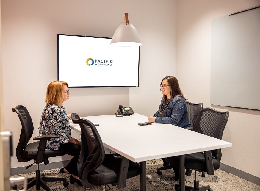Two women in office sitting at table for consultation Two women in office sitting at table for consultation