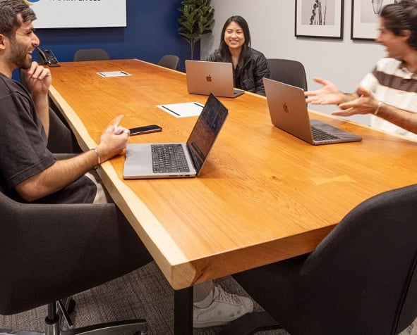 1 professional woman and 2 professional men using hourly meeting room rental for team collaboration