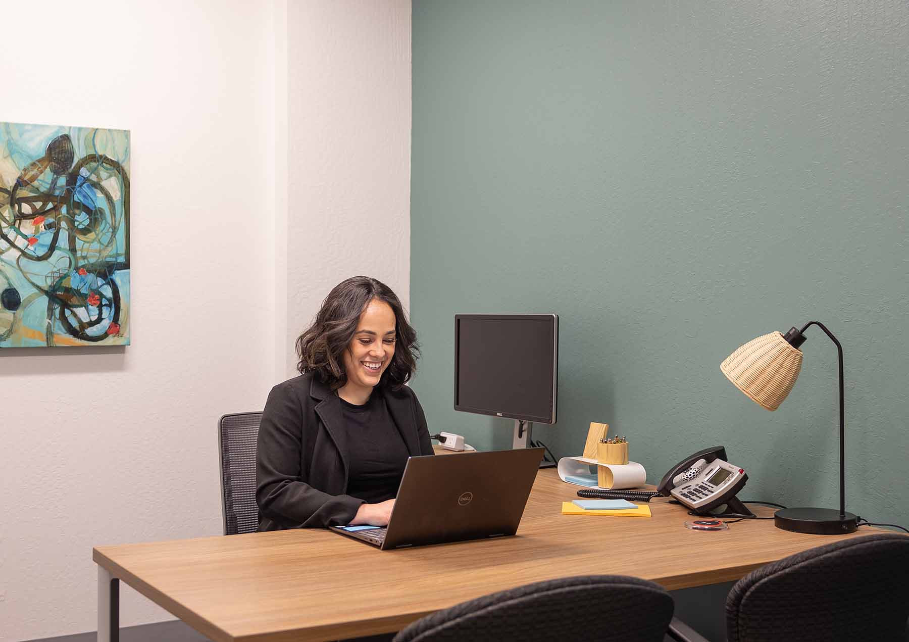 Woman working on laptop at desk in private office space in Cupertino