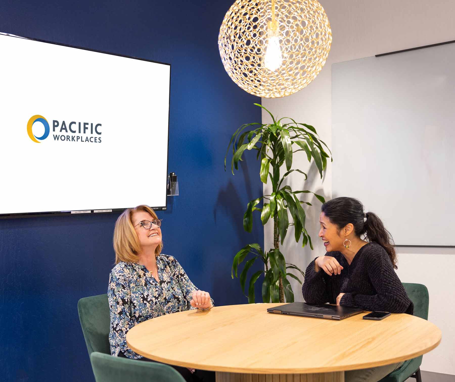 Two women at a table in a meeting room in at Pacific Workplaces
