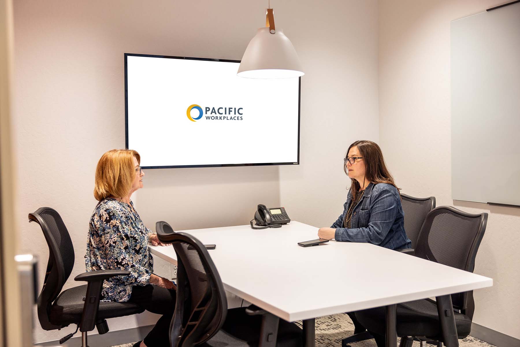 Two women sitting at table in meeting room in Sacramento Two women sitting at table in meeting room in Sacramento