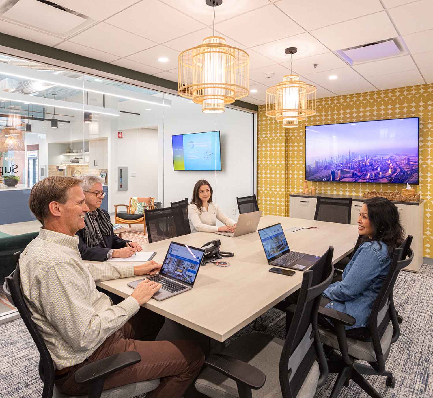 Four people sitting at table in meeting room in coworking space in San Jose
