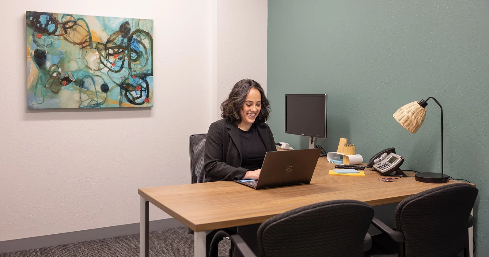 Woman working at desk with laptop in private office space in Roseville