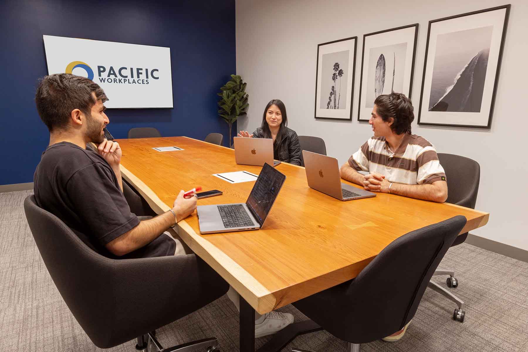 two men and a woman work on laptops in a meeting room at pacific workplaces San Francisco